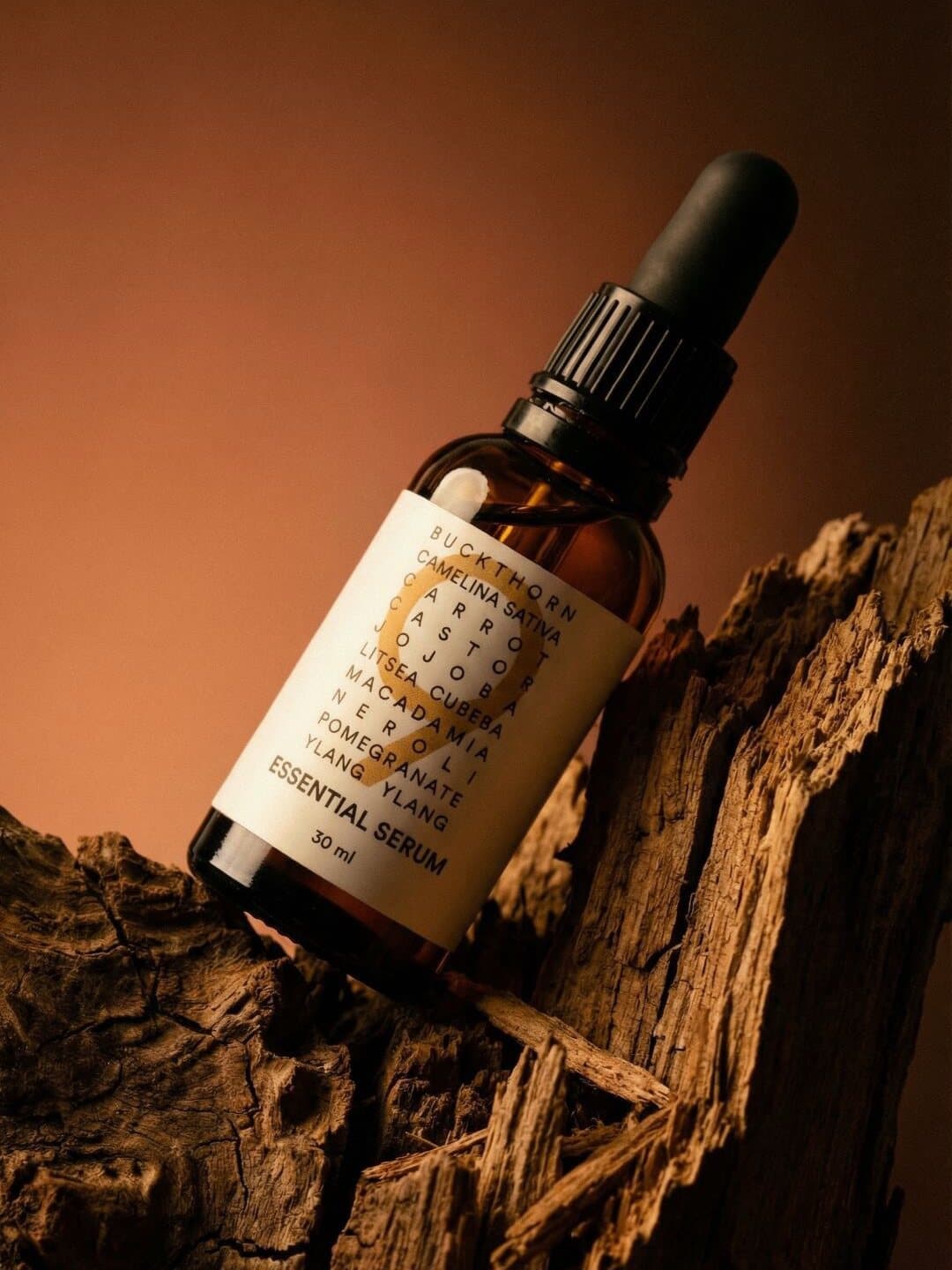 Das 9 Essential Serum auf einem Stück Holz, warmes Licht